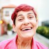 Portrait of Happy Senior woman smiling at camera with background city - Soft focus on hair